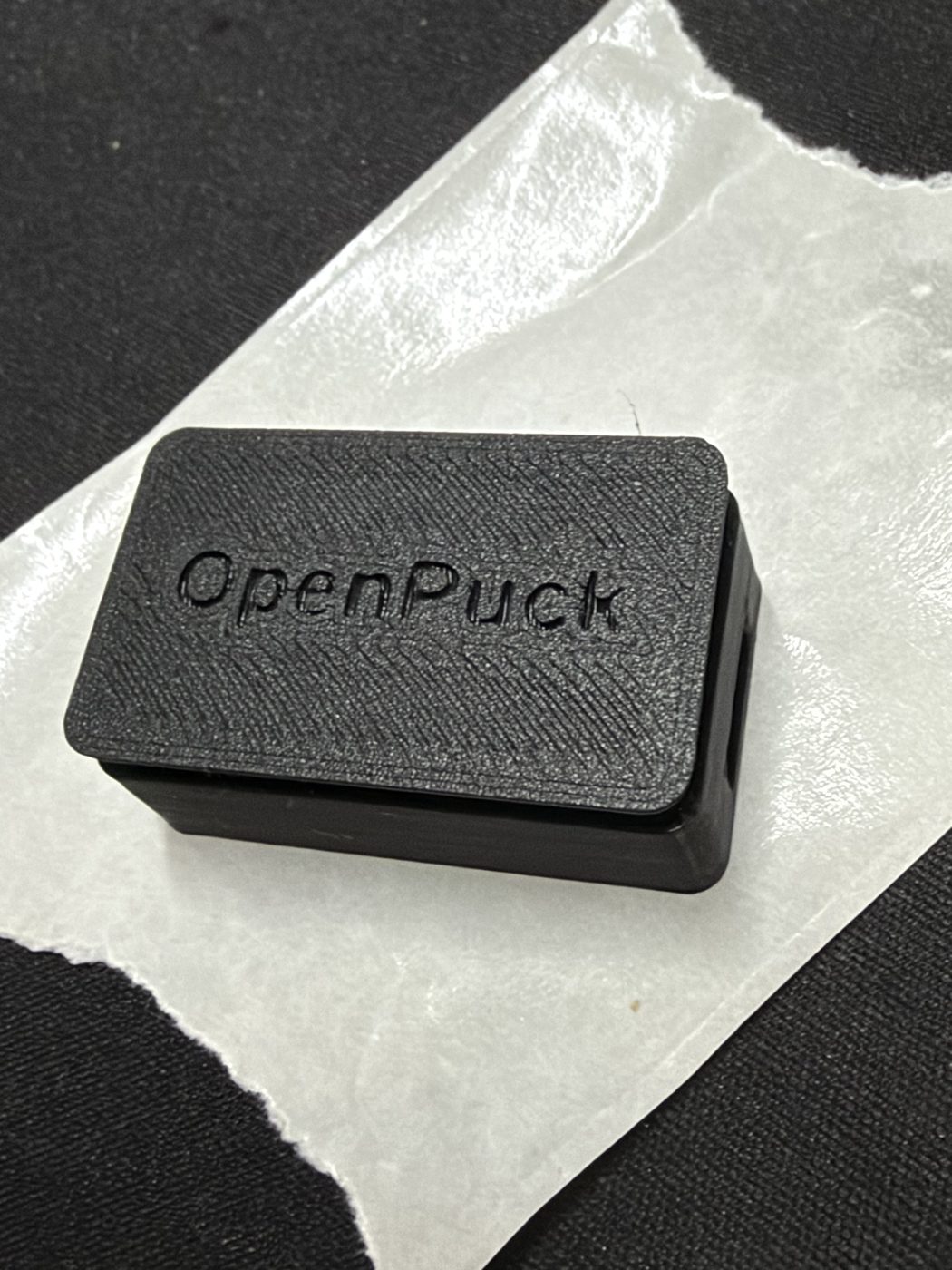 The finished OpenPuck: the closed black case with OpenPuck embossed on the lid and the USB-C port visible at the top.